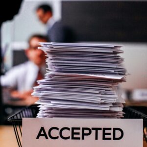 Pile of papers with 'Accepted' label in a busy office setting, highlighting information management.